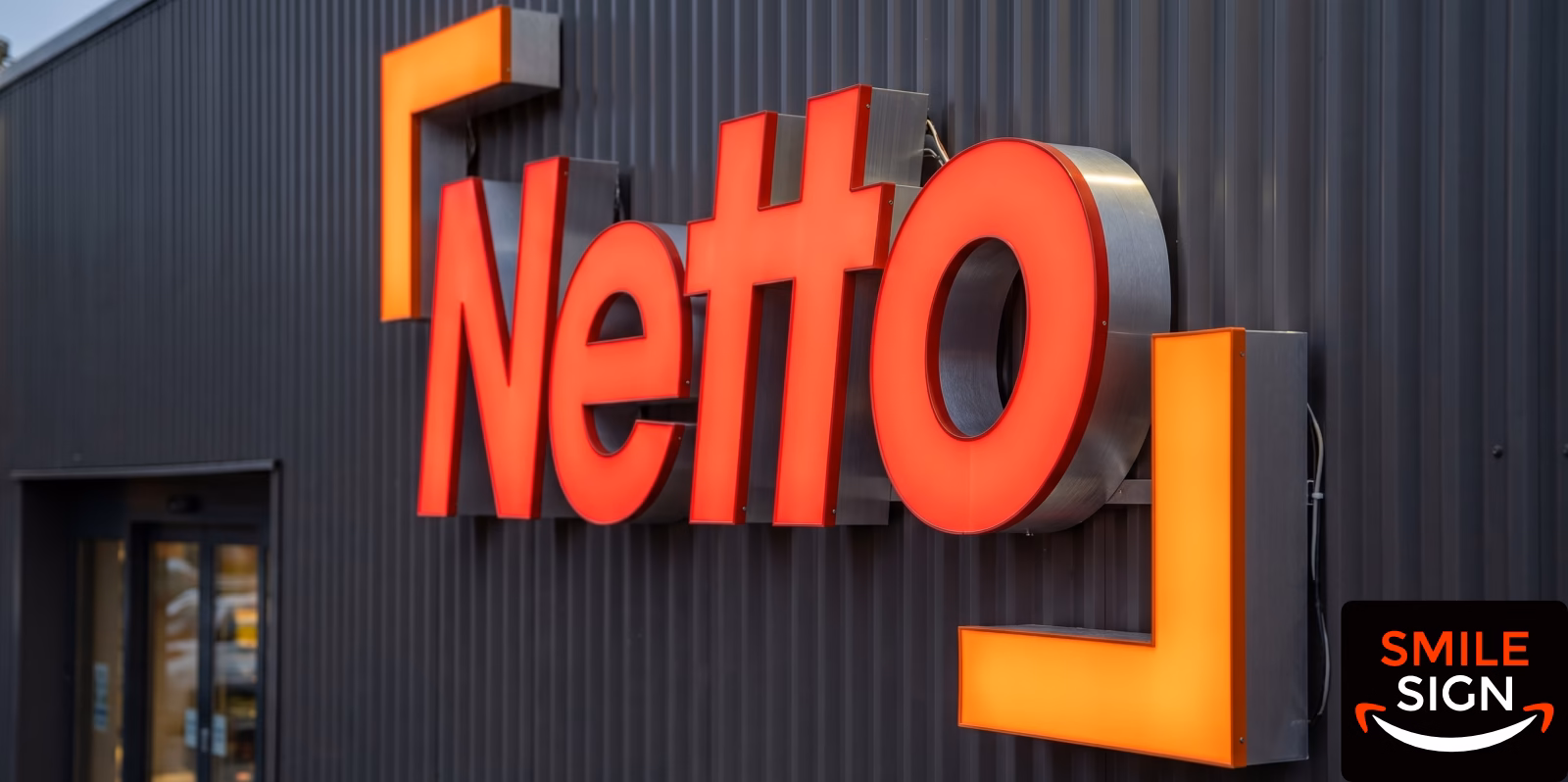 Red frontlit 3D channel letters mounted on metal wall facade for Netto by Smile Sign